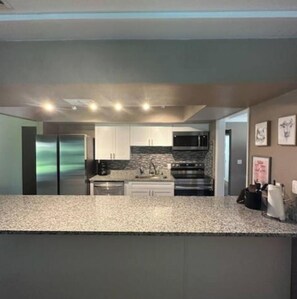 A modern kitchen with stainless steel appliances, white cabinetry, and granite countertops.