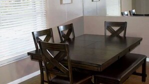 Une table de salle à manger rectangulaire, accompagnée de quatre chaises, d’un banc et d ’un miroir accroché au mur.