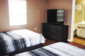 A bedroom with a bed, a dresser, a television, and a window.