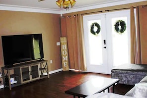 Ein Wohnzimmer mit Fernseher, einer Couch, einem Couchtisch und einem Schild mit der Aufschrift 'HOME'.