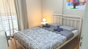Een enkel bed met een metalen frame, een beddengoed met een patroon en twee blauwe kussens.