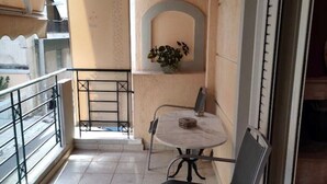 Een balkon met betegelde vloer, een tafel, twee stoelen, een bloempot en een balustrade.