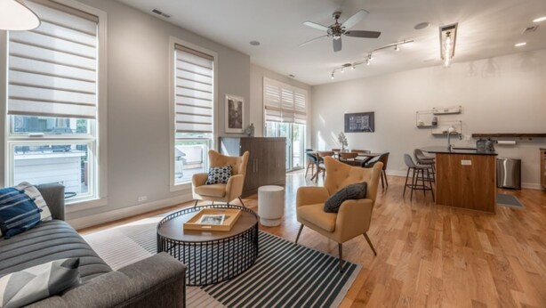 Una sala moderna con sofá, sillones, una mesa de centro y un comedor con isla de cocina.