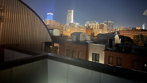 Un horizonte urbano al anochecer con edificios modernos y un rascacielos destacado.