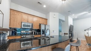 Una cocina moderna con armarios de madera, electrodomésticos de acero inoxidable y encimera de granito negro.