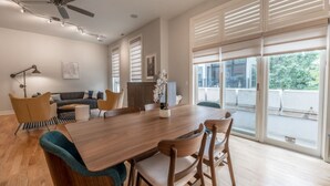 Un comedor con una mesa y sillas de madera, un ventilador de techo y ventanas amplias con persianas.