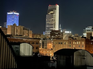 A city skyline at night with illuminated buildings, including a prominent blue-lit building and a tall skyscraper. - Marcy Condo (Omaha)