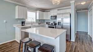 A modern kitchen with white cabinets, stainless steel appliances, and a large island with stools.