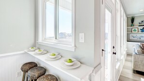 A kitchen with a white countertop, a window, and a door leading to another room. - Spacious Luxe Home|Private Pool/Hot Tub (North Topsail Beach)