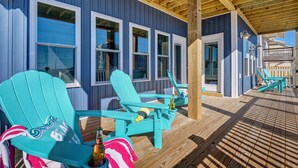 A wooden deck with two turquoise Adirondack chairs, a bottle, and a striped towel. - Spacious Luxe Home|Private Pool/Hot Tub (North Topsail Beach)