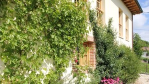 Un edificio con fachada blanca, balcones de madera y una sección de ladrillo.