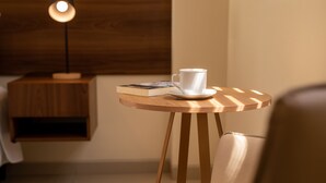 A cozy seating area with a round wooden table, a white cup, and a book. - Equipetrol Suites Apart Hotel (Santa Cruz)