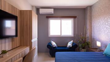 Un dormitorio moderno con una cama grande, un televisor montado en la pared, una ventana y una planta.
