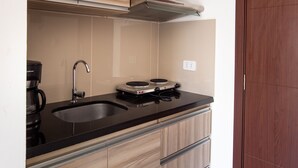 A modern kitchen with wooden cabinets, a black countertop, and a built-in stove. - Equipetrol Suites Apart Hotel (Santa Cruz)