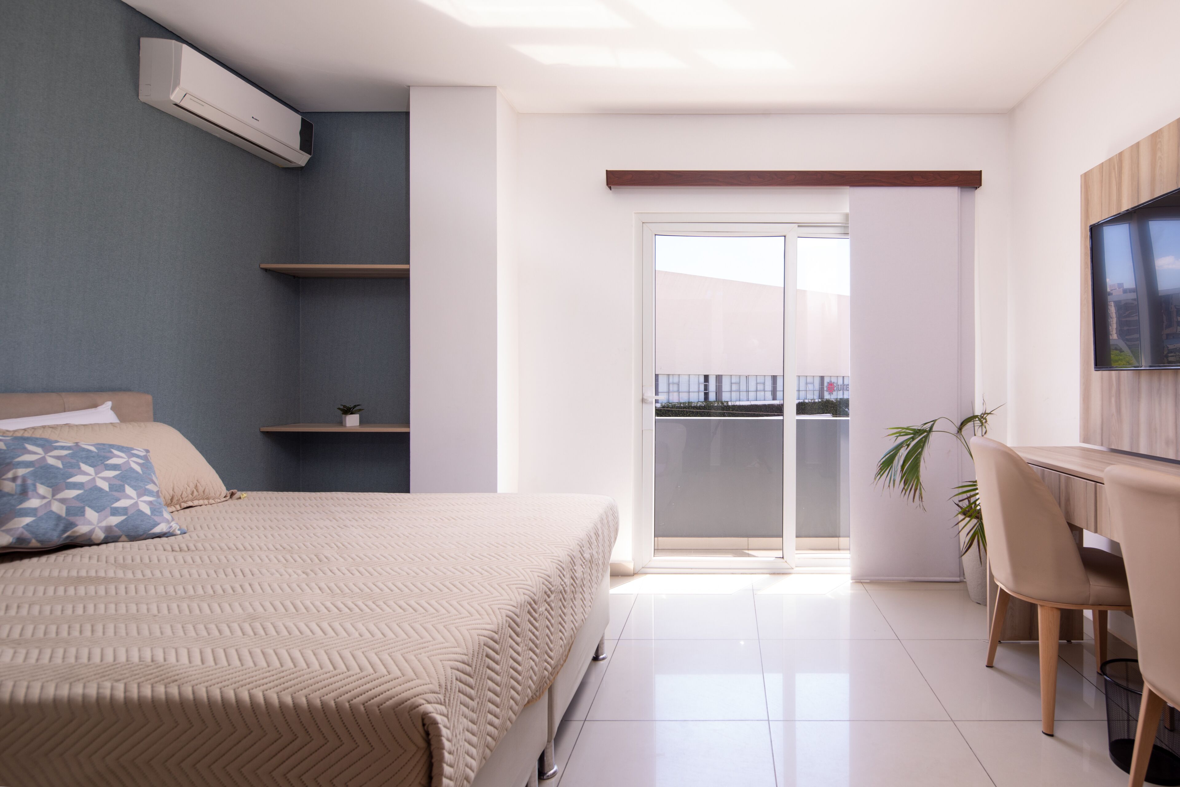 A modern bedroom with a bed, bedside tables, a desk, and a TV.