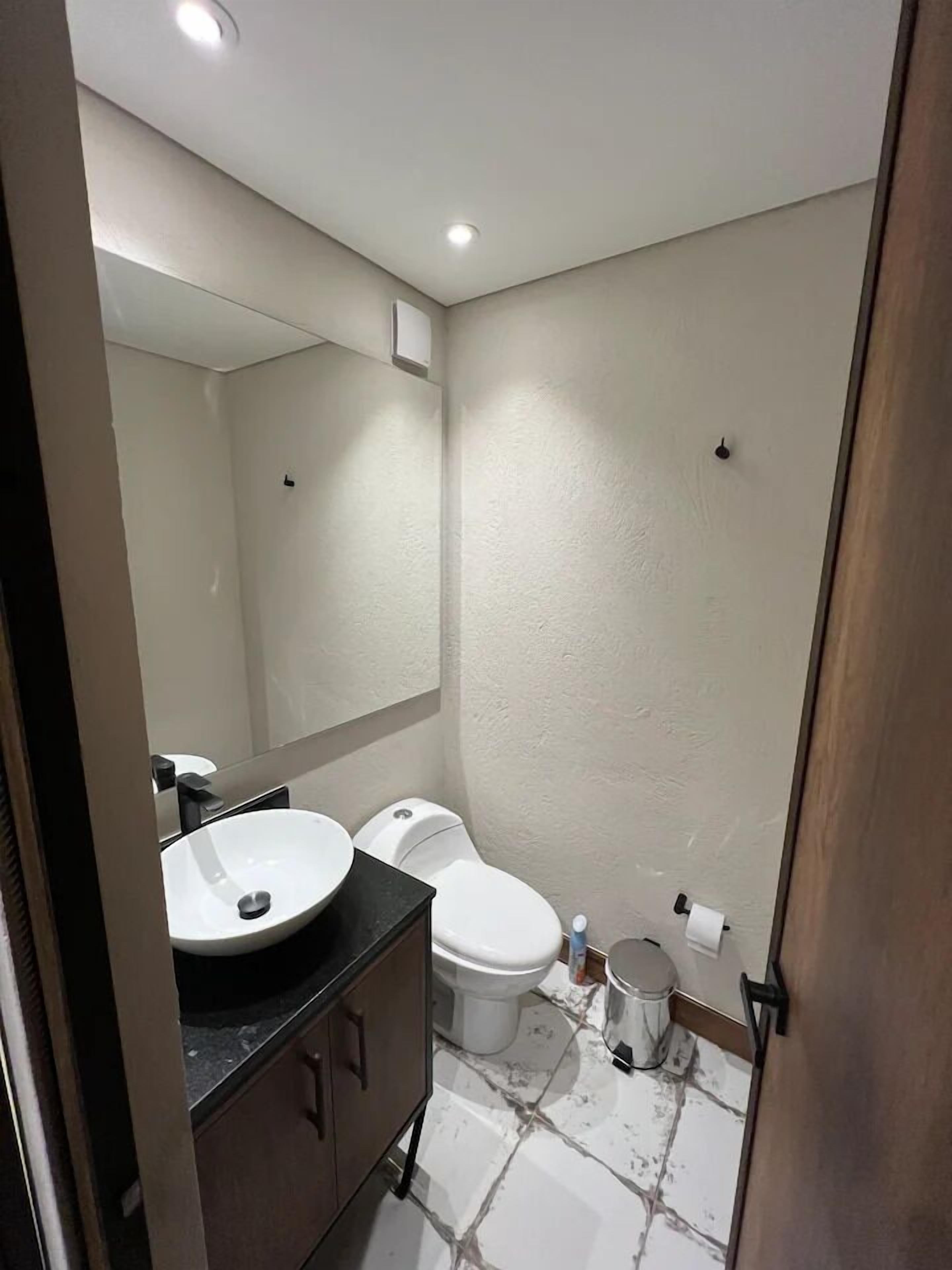 A bathroom with a white sink, toilet, and mirror.