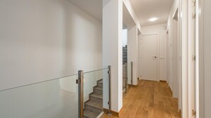 A modern interior with a wooden floor, glass railings on a staircase, and white walls. - Newly built house with private pool (Begur)