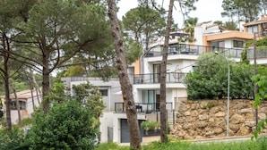 A multi-story residential building with balconies, surrounded by trees and greenery. - Newly built house with private pool (Begur)