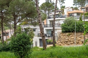 Un immeuble résidentiel à plusieurs étages, doté de balcons et entouré d’arbres et de verdure.