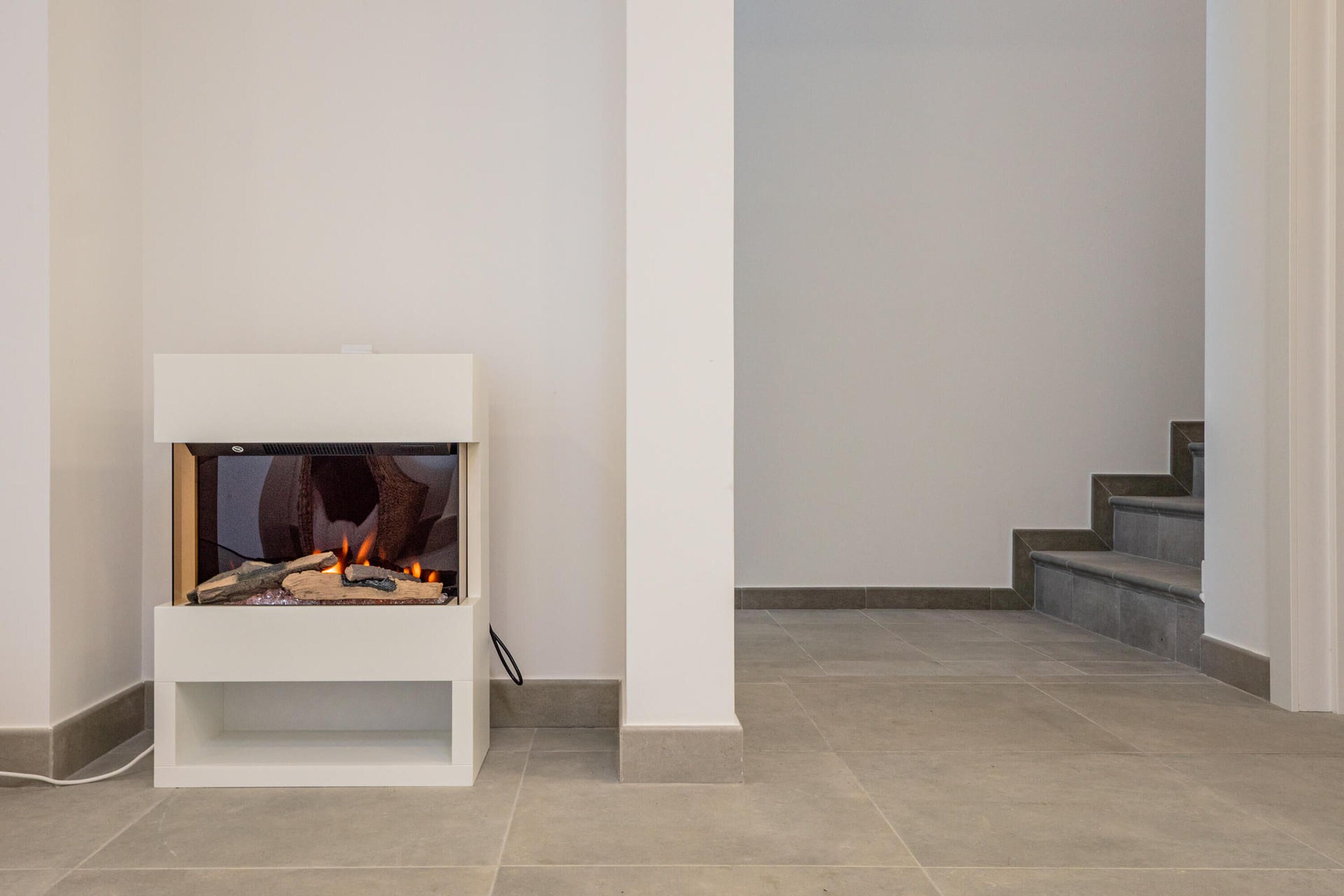 A modern fireplace with a white mantel, a visible fire, and a clean, minimalist interior design.