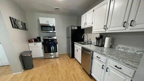 A kitchen with white cabinets, stainless steel appliances, and a granite countertop.