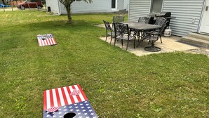 Un césped con un área de juegos temática de la bandera estadounidense, una mesa de patio y sillas.