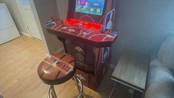 An arcade machine labeled "NBA JAM" with a basketball-themed stool.