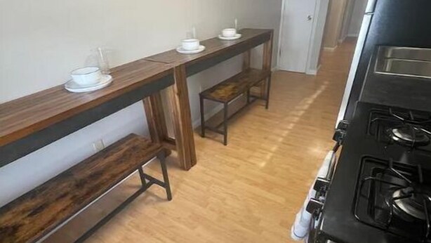 Una cocina con un banco de madera, una mesa pequeña y una estufa.