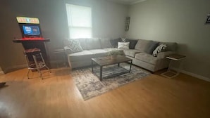 Una sala de estar con sofá, mesa de centro y una mesita con lámpara.