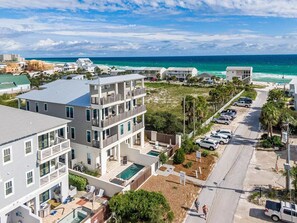 A multi-story residential building with balconies, a swimming pool, and a view of the ocean.