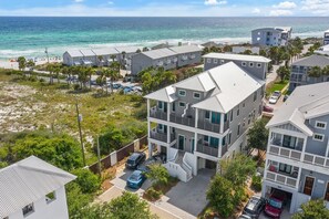 A coastal residential area with modern two-story houses, a beach, and a clear view of the ocean.