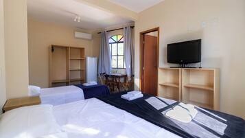 Hotelkamer met twee bedden, een televisie, een bureau en een raam met gordijnen.