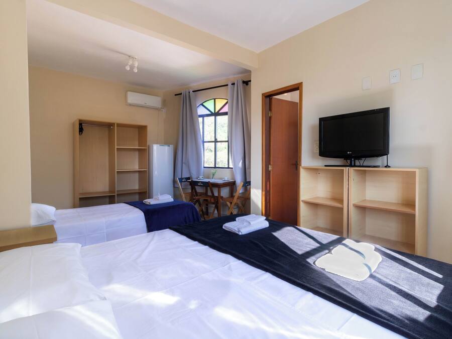 Hotelkamer met twee bedden, een televisie, een bureau en een raam met gordijnen.