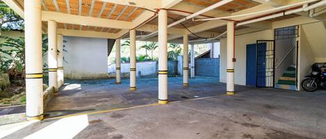 An open covered parking area with concrete pillars and a wooden ceiling.