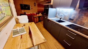 Una cucina compatta con un tavolo di legno, un piano cottura integrato e mobili scuri.