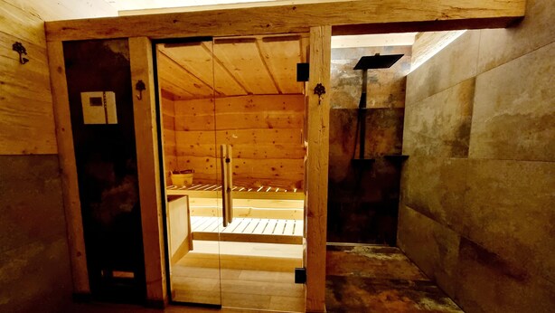 Un interno in legno con area sauna, comprendente una panca e una porta per la sauna.
