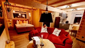 Una camera accogliente con un divano rosso, un tavolino in legno e un letto con cuscini rossi.