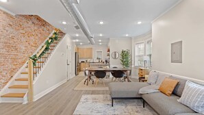 Un interior moderno con una escalera, un comedor y una sala de estar con un sofá y una alfombra.