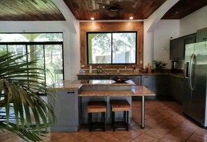 Cozinha com ilha central, armários de madeira e uma janela grande.