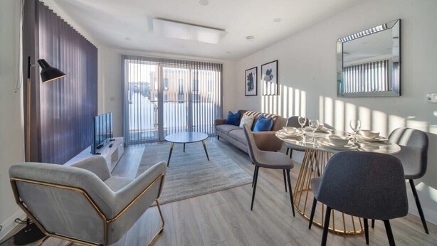 A modern living room with a sofa, two round tables, and a dining table set for four. - Contemporary 2 Bedroom Apartment in Ashford (Ashford)