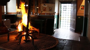 Habitación con una chimenea central, una zona de bar y vistas al exterior a través de una ventana.