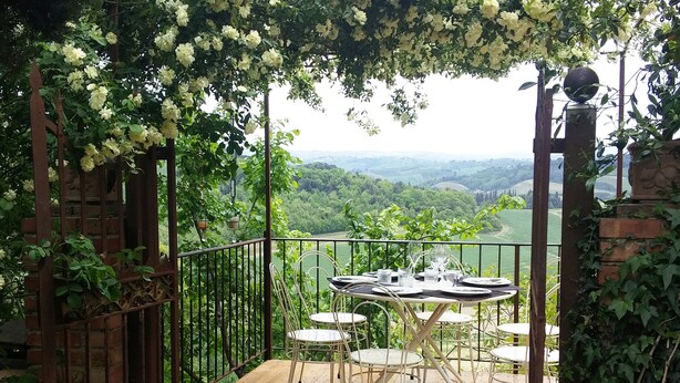 Una terraza con mesa y sillas, rodeada de follaje y una vista panorámica.
