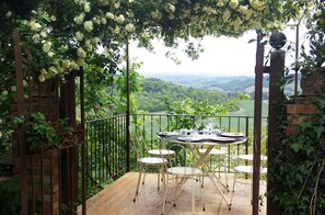 Une terrasse avec une table et des chaises, entourée de verdure et offrant une vue panoramique.
