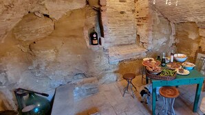 Interior rústico de piedra con una mesa de comedor dispuesta para una comida, una botella de vino y un perro pequeño.