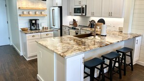 Una cocina amplia con armarios blancos, una isla grande con taburetes de bar y electrodomésticos modernos.
