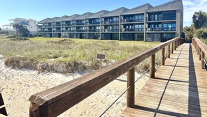 Un hotel frente al mar con varios balcones, un muelle de madera y una zona de playa arenosa.