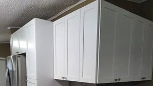 Eine Küche mit weißen Schränken, einem Edelstahlkühlschrank und einer Marmorarbeitsplatte.