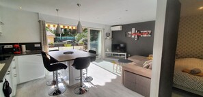 A modern kitchen with a dining area, a sofa, and a TV in a living room. - Appartement LE Silene (Sainte-Maxime)