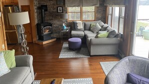 Un salon chaleureux avec un mur en pierre, une cheminée, un canapé et un plafond en bois.