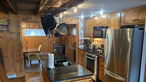 Une cuisine avec des meubles en bois, un réfrigérateur en acier inoxydable, une cuisinière et un four à micro-ondes.